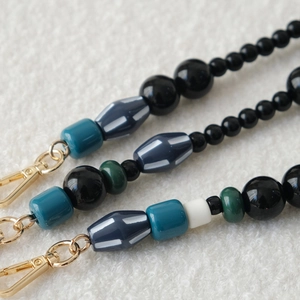 Detailed view of colorful acrylic beaded chains with gold lobster clasps on white fabric