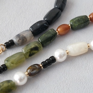 Close-up of multicolored acrylic beads and white pearls with golden metal spacers