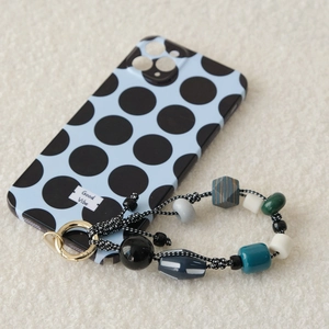Détail d'une coque bleue à pois avec dragonne en perles colorées et anneau en métal doré