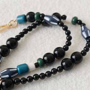 Macro shot of colorful acrylic beads and golden metal spring clasp on white fabric