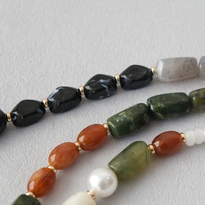 Detailed close-up of acrylic beads in amber and green with gold-tone spacers on leather