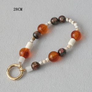 Detail of 28cm acrylic beaded phone strap with orange and marble beads and gold clasp