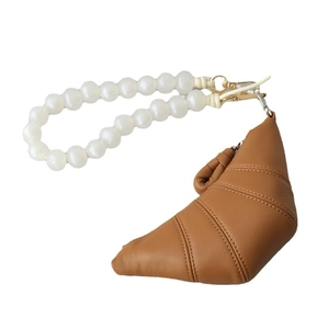Croissant-shaped caramel leather bag with a white pearl bead handle on a white background