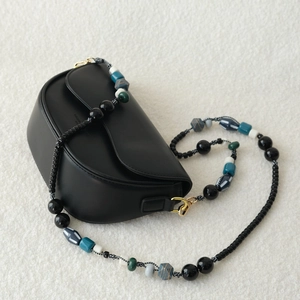 Détail de la sangle en perles acryliques sur un sac bandoulière noir minimaliste