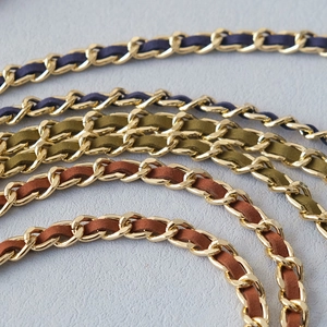 Close-up of golden metal woven chain straps with navy blue, green, and brown suede inserts