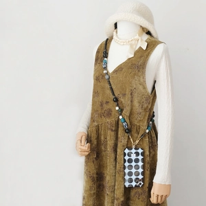 Vue détaillée du cordon de téléphone à perles avec coque bleue à pois sur mannequin