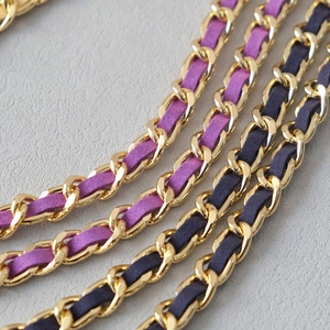 Close-up of golden metal chain strap with interwoven purple and navy leather detail