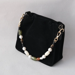 Detail of black velvet shoulder bag featuring luxury acrylic beaded strap and gold hardware