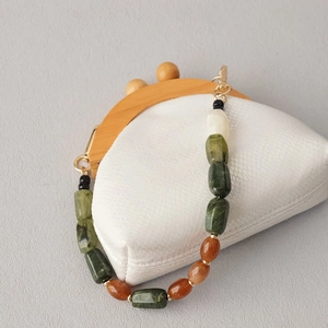 Close-up of multicolor acrylic beads chain with gold clasps on white leather handbag