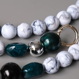 Detailed macro view of colorful resin beads with marble textures and golden metal clasp