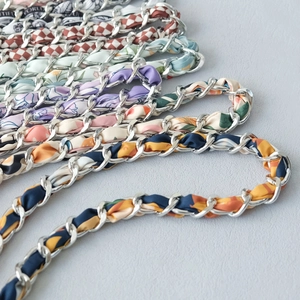 Close-up of assorted silk scarf intertwined with silver metal chain straps for handbags