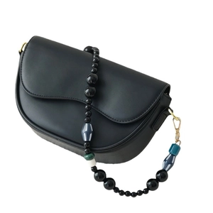 Black matte leather saddle bag featuring a decorative colorful acrylic beaded shoulder strap