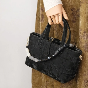 Detailed close-up of black Cannage quilted handbag with marble bead chain and metal hooks