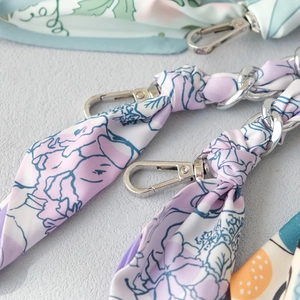 Detailed close-up of woven silk scarf chain straps with silver lobster clasps for bags