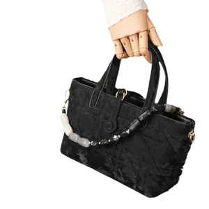 Black velvet tote bag with cannage quilting and marble bead handle on wooden hand