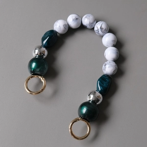 Detail of acrylic bead bag chain with marble pattern, green resin, and gold spring buckles