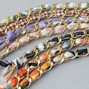 Close-up of golden metal chain straps with colorful silk scarves and lobster clasps