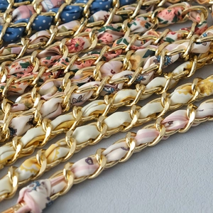 Detailed view of luxury gold metal chains woven with colorful silk scarves and floral patterns