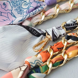 Close-up of golden metal chain straps woven with patterned silk scarves for handbags