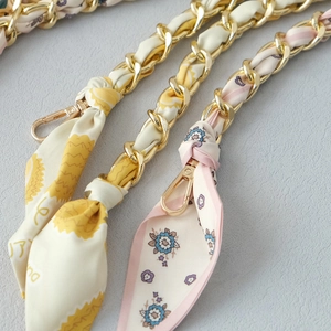 Detail of silk scarf intertwined with gold metal chain strap featuring lobster clasps