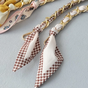 Close-up of golden metal chain straps with colorful floral and houndstooth silk ribbons