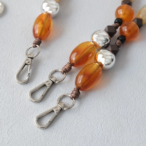 Close-up of amber acrylic beads and silver metallic spheres on a hand-woven bag strap