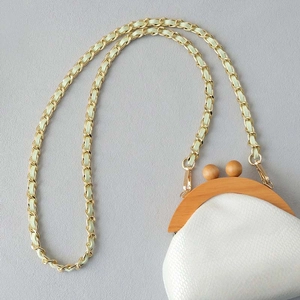 Macro view of gold metal chain with light green woven leather and crocodile texture bag