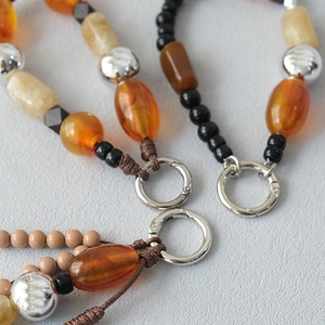 Detail of acrylic bead strap showing amber and cream beads with silver spring clasp