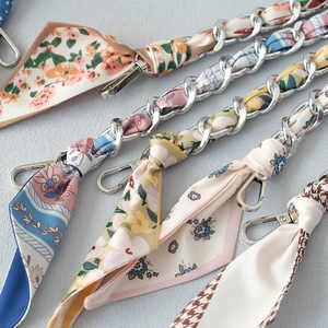 Detail of silk scarf interwoven with silver metal chain straps for handbags and accessories