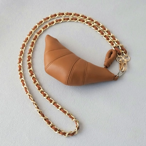 Brown leather croissant bag with stylish gold chain strap and knotted detail accents