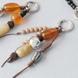 Macro view of multi-element beaded chain with amber acrylic, silver metal, and marble beads