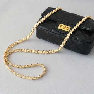 Detail of the golden chain strap and classic quilted black leather on the crossbody bag
