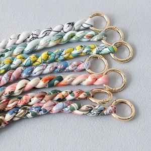 Detail of six printed fabric woven bag charms with polished golden spring rings