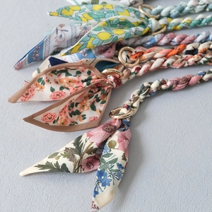Close-up of floral silk scarves braided with golden metal rings for handbag accessories