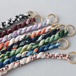 Détail de bandoulières en soie pour sacs à main avec anneaux dorés et motifs variés