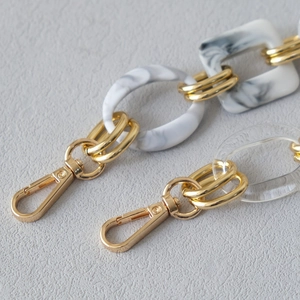 Detail of red marble resin chain strap with gold metal lobster clasp and rings