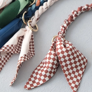 Détail de bandoulières de sac en foulard de soie avec fermoirs dorés et carreaux