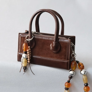 Detailed close-up of brown patchwork leather bag with retro acrylic beaded strap accessory