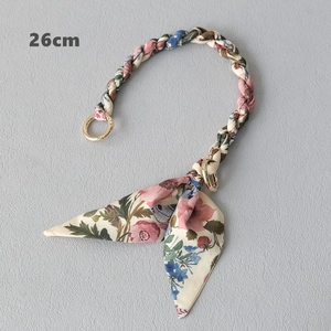 Detail view of 26cm scarf woven handbag strap with floral patterns and gold spring clasps