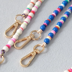Macro detail of acrylic bead straps with colorful clay discs and gold lobster clasps