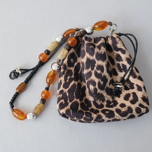 Detail of leopard print drawstring bag with colorful acrylic beaded handle strap