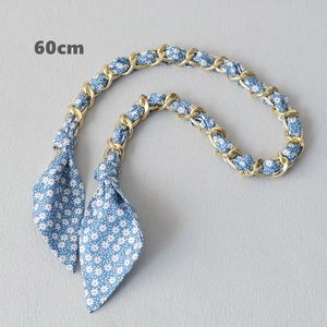 Detail of 60cm golden chain intertwined with light blue floral silk scarf for handbags