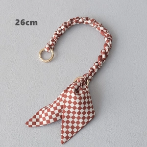 Détail de la poignée de sac à damier rouge de 26 cm avec nœud et anneaux dorés