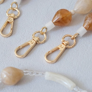 Close-up of apricot acrylic bead chain with amber drop charms and gold metal clasps