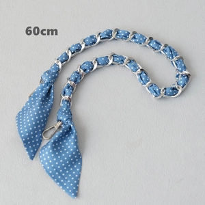 Close-up of 60cm blue polka dot silk scarf entwined with silver chain bag strap