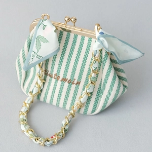 Detail of green striped fabric handbag with silk scarf chain and vintage gold clasp