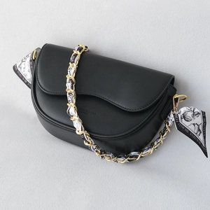 Elegant black saddle bag with gold chain strap and floral silk scarf detail decoration
