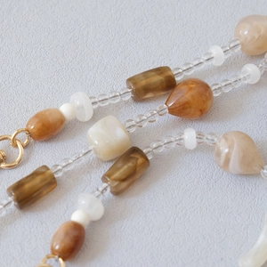 Macro detail of amber and cream acrylic beads with golden metal clasps for bag straps