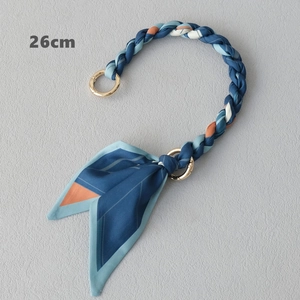 Détail d'une bandoulière tressée en soie de 26 cm avec anneaux dorés et motif bleu orange