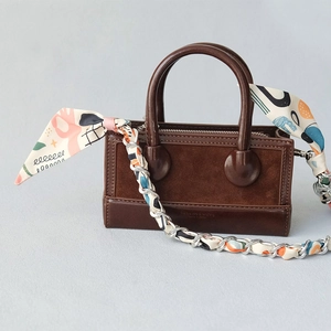 Dark brown leather handbag with luxury silk scarf wrapped around a metal chain strap
